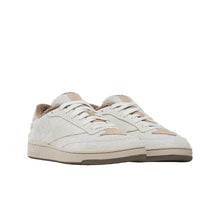 Load image into Gallery viewer, A pair of low-top sneakers in off-white suede and beige leather, featuring a fuzzy beige lining and white laces, set against a solid black background.