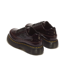 Load image into Gallery viewer, A pair of Dr. Martens low-top platform sneakers in glossy crocodile-embossed leather, featuring a deep burgundy color and signature yellow stitching around the black sole.