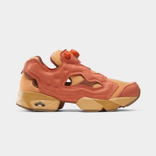 Load image into Gallery viewer, A side-profile view of a Reebok Instinct Prime 2 sneaker in a warm terracotta orange and tan colorway, featuring a unique cutout design and a dial closure, set against a light gray background.
