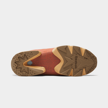 Load image into Gallery viewer, The outsole of a Reebok boot, showing a textured brown and tan rubber tread with the Reebok brand name embossed on the right side, photographed against a light gray background.