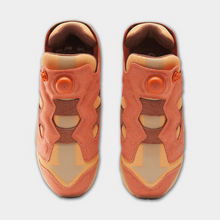 Load image into Gallery viewer, A pair of low-top sneakers shown from a top-down view, featuring a color-blocked design in shades of terracotta orange, tan, and brown suede, with a circular dial closure on the side.